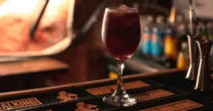 La Factoría bar interior with rustic decor and patrons enjoying cocktails.